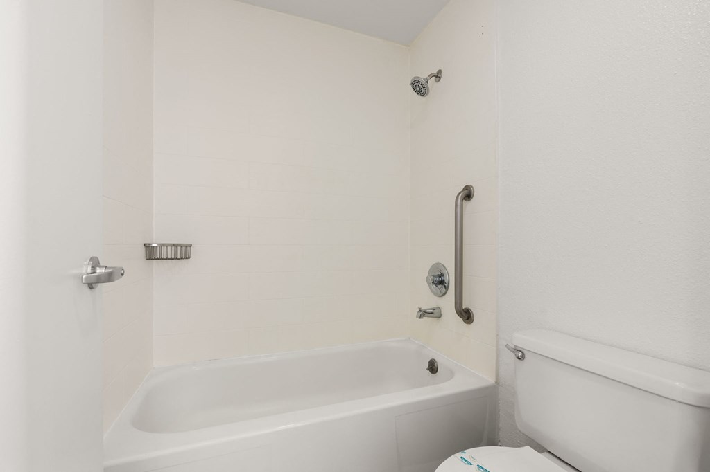 a white bathroom with a tub and a toilet at AVIA Lofts on Parkway Apartments, Vancouver, WA