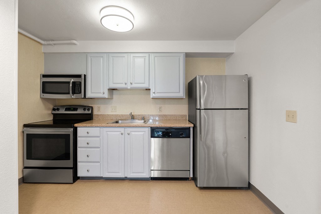 a kitchen with stainless steel appliances and white cabinets at AVIA Lofts on Parkway Apartments, Vancouver