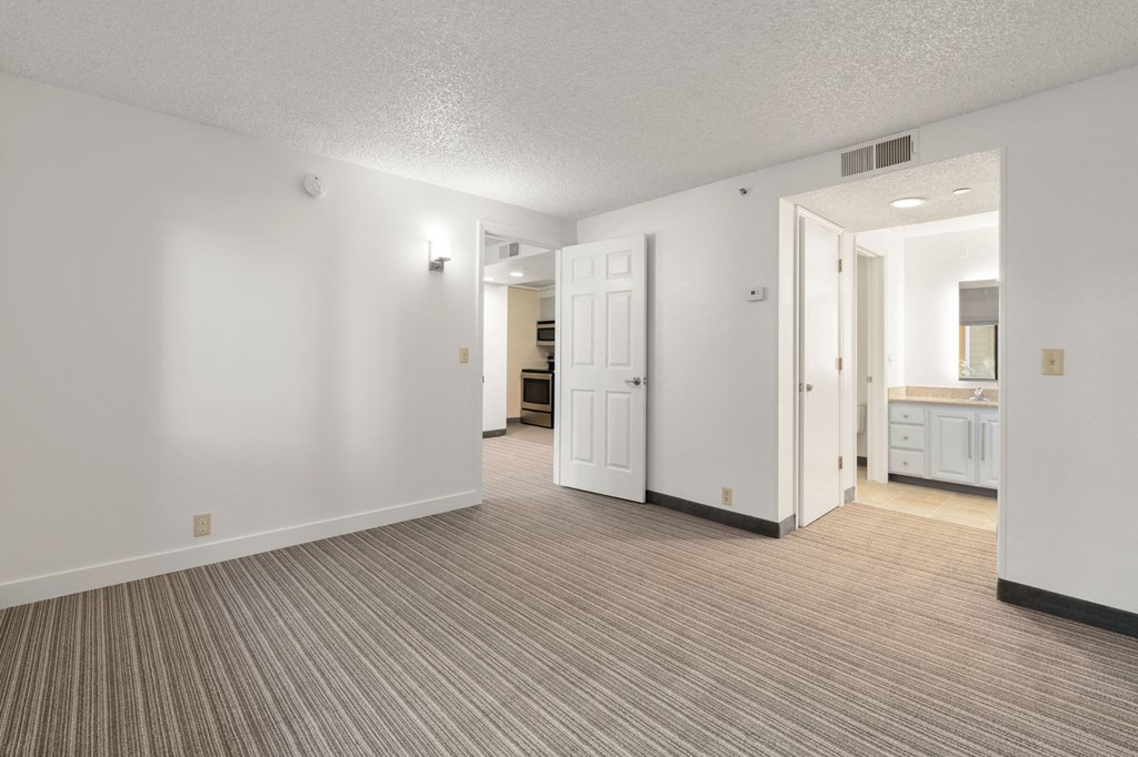 the living room and kitchen of an apartment with a carpeted floor and white walls at AVIA Lofts on Parkway Apartments, Vancouver, Washington