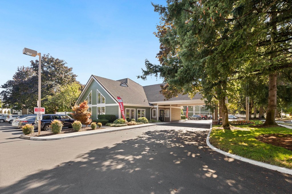 A parking lot in front of a building with a green lawn and trees. at AVIA Lofts on Parkway, Washington