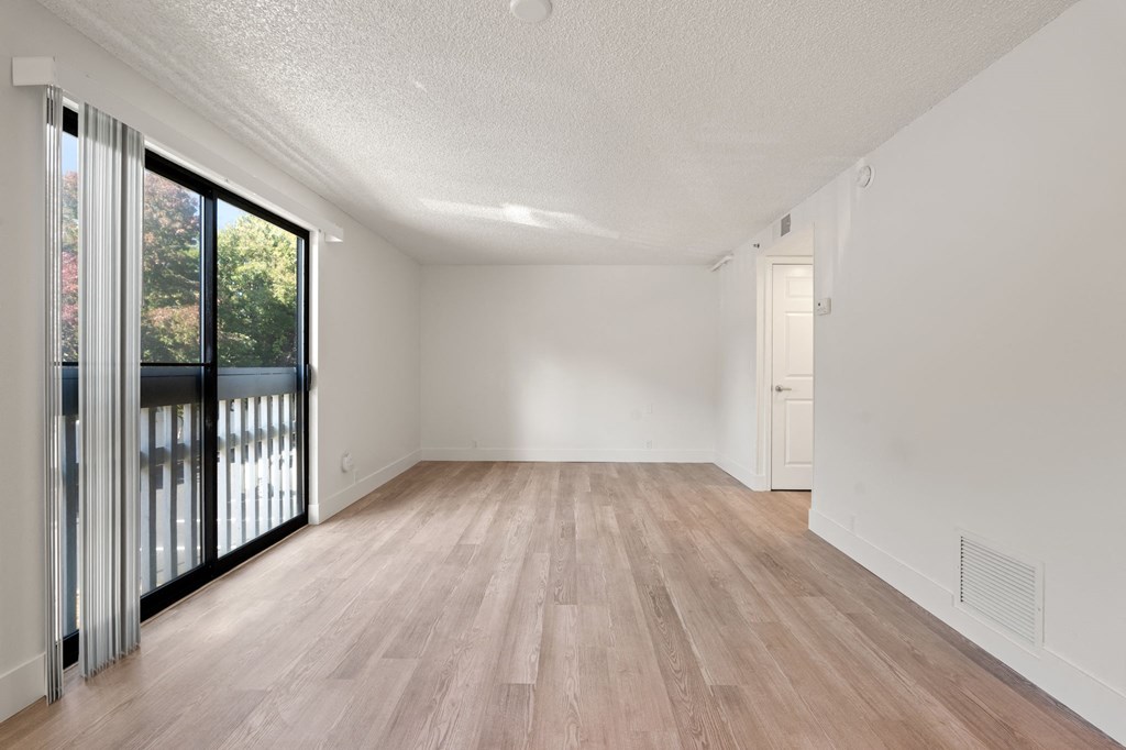 an empty living room with a sliding glass door to a balcony at AVIA Lofts on Parkway Apartments, Vancouver, Washington
