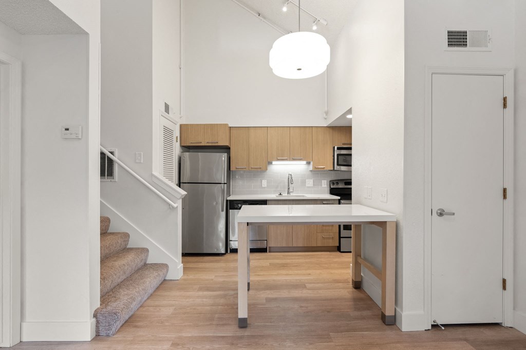 a kitchen with a white table and a stainless steel refrigerator at AVIA Lofts on Parkway Apartments, Washington