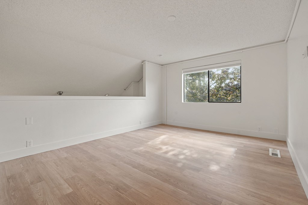 the living room of an empty house with wood floors and a window at AVIA Lofts on Parkway Apartments, Vancouver, WA, 98662