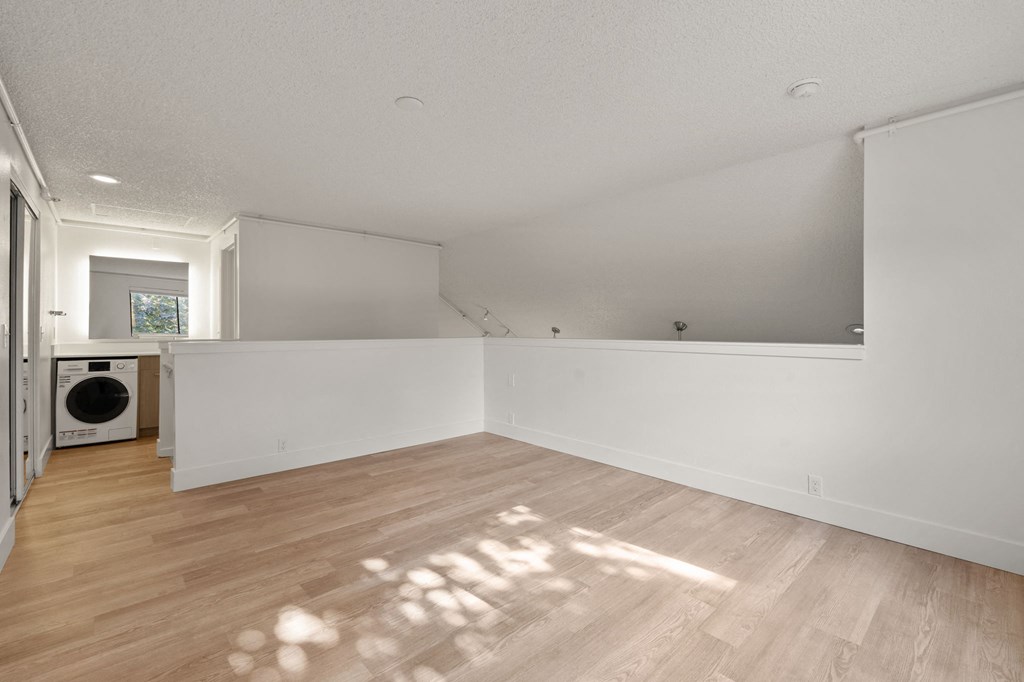 the living room and laundry room of a renovated house with white walls and wood floors at AVIA Lofts on Parkway Apartments, Washington, 98662
