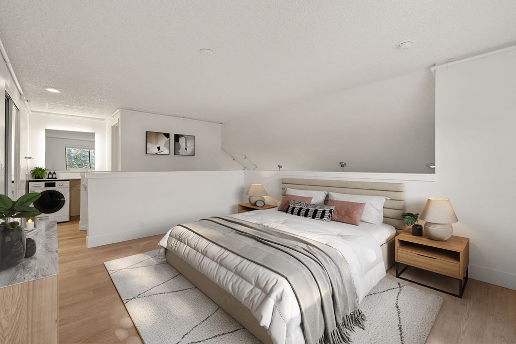 A bedroom with a large bed and a wooden nightstand. at AVIA Lofts on Parkway Apartments, Vancouver, WA