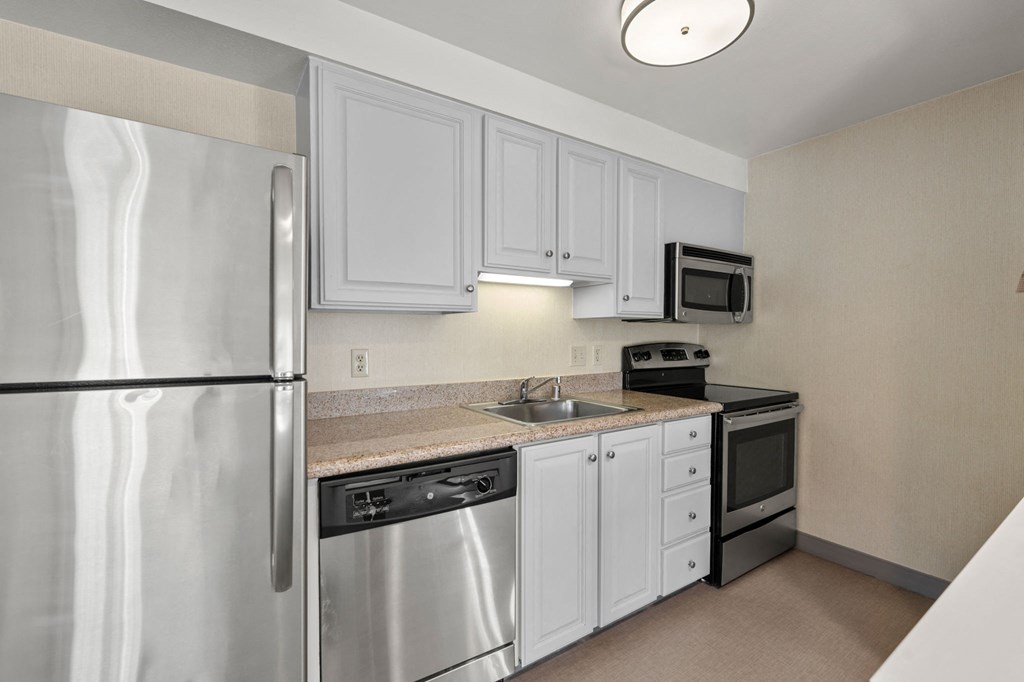 a kitchen with stainless steel appliances and white cabinets at AVIA Lofts on Parkway Apartments, Vancouver