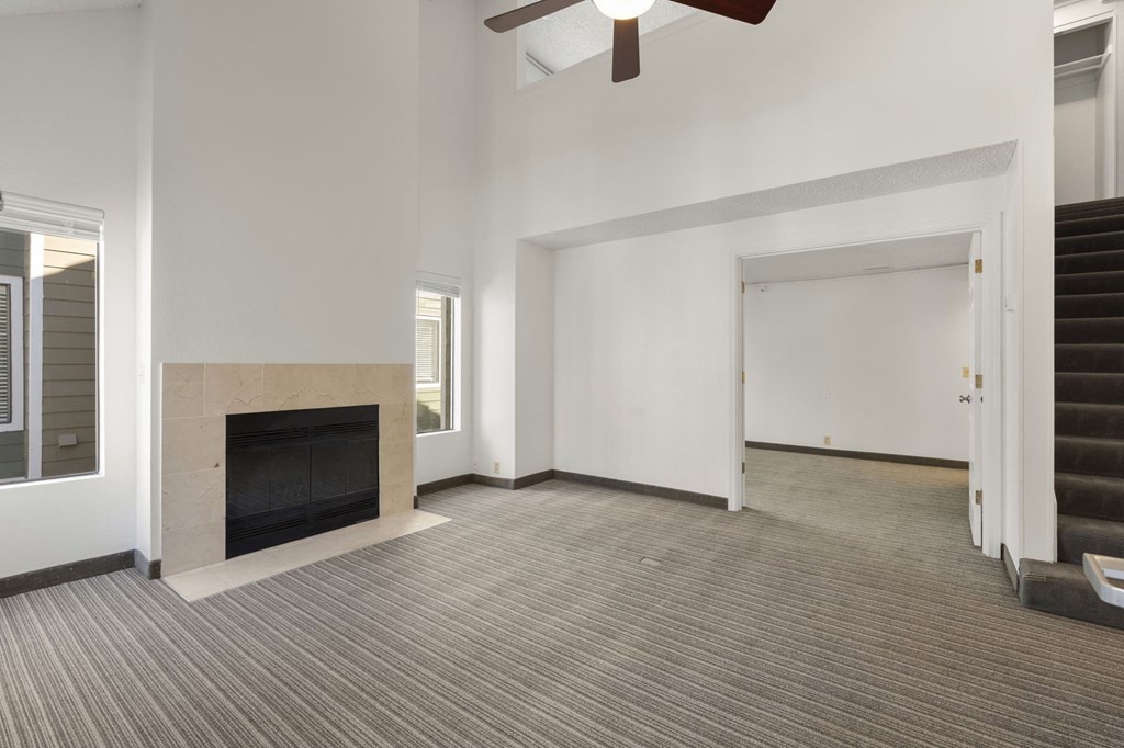 an empty living room with a fireplace and a ceiling fan at AVIA Lofts on Parkway Apartments, Vancouver, WA