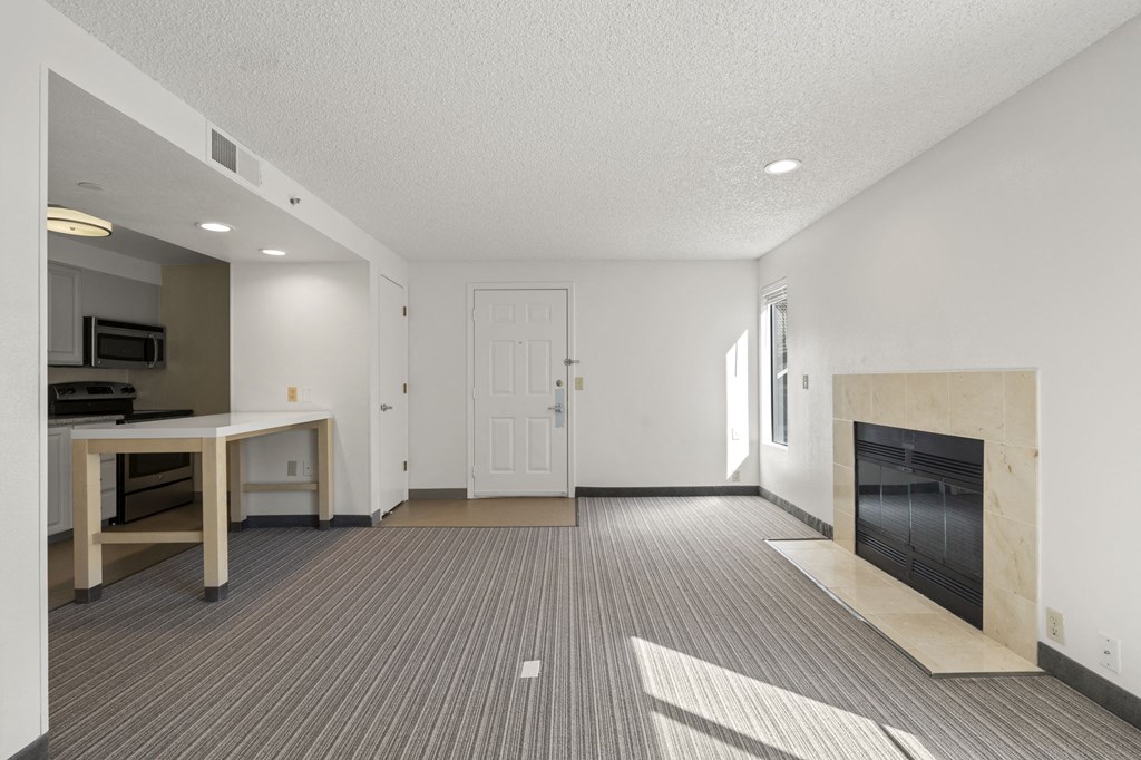 an empty living room with a fireplace and a kitchen at AVIA Lofts on Parkway Apartments, Washington