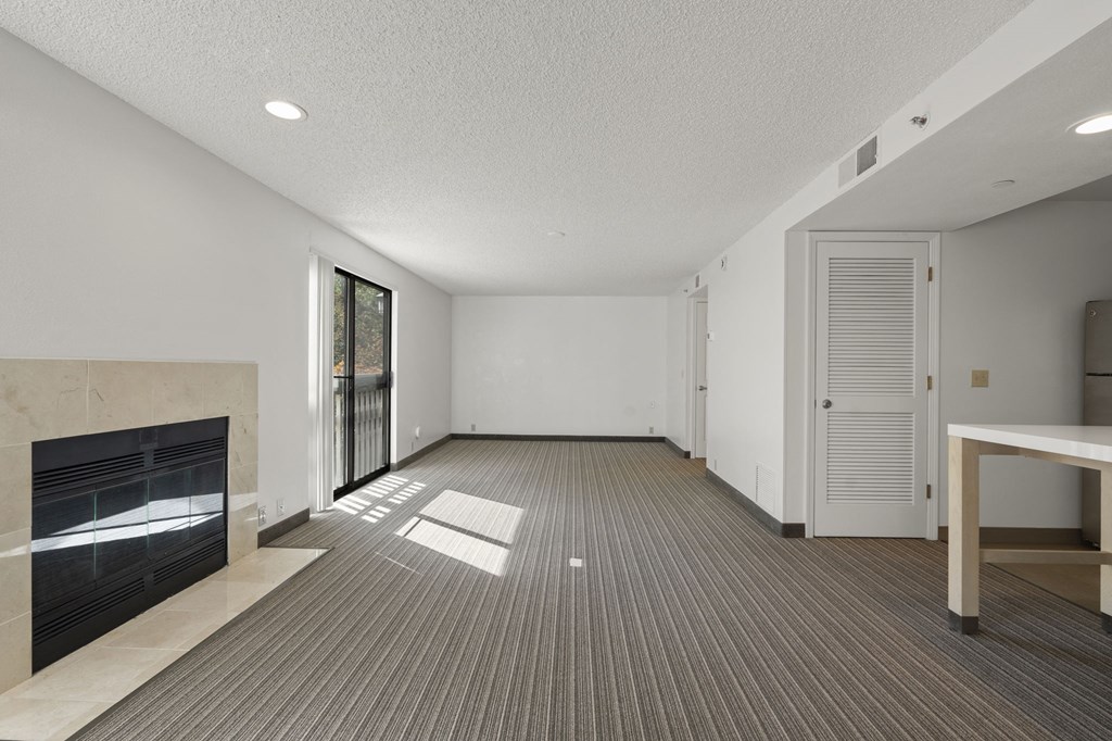 an empty living room with a fireplace and a door to a hallway at AVIA Lofts on Parkway Apartments, Vancouver, WA, 98662