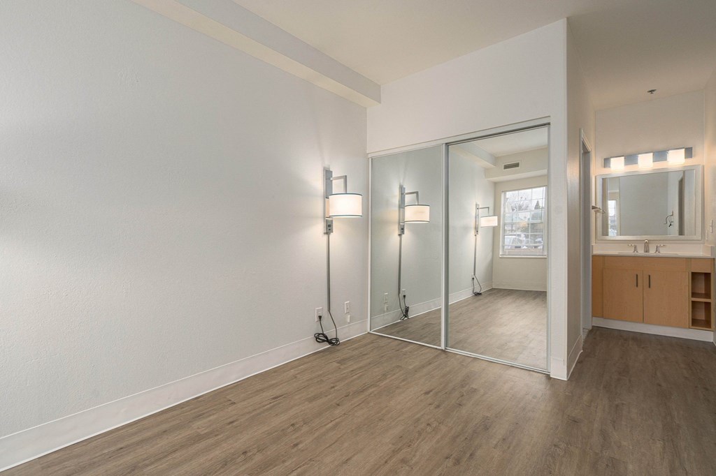 an empty living room with a mirror and a bathroom