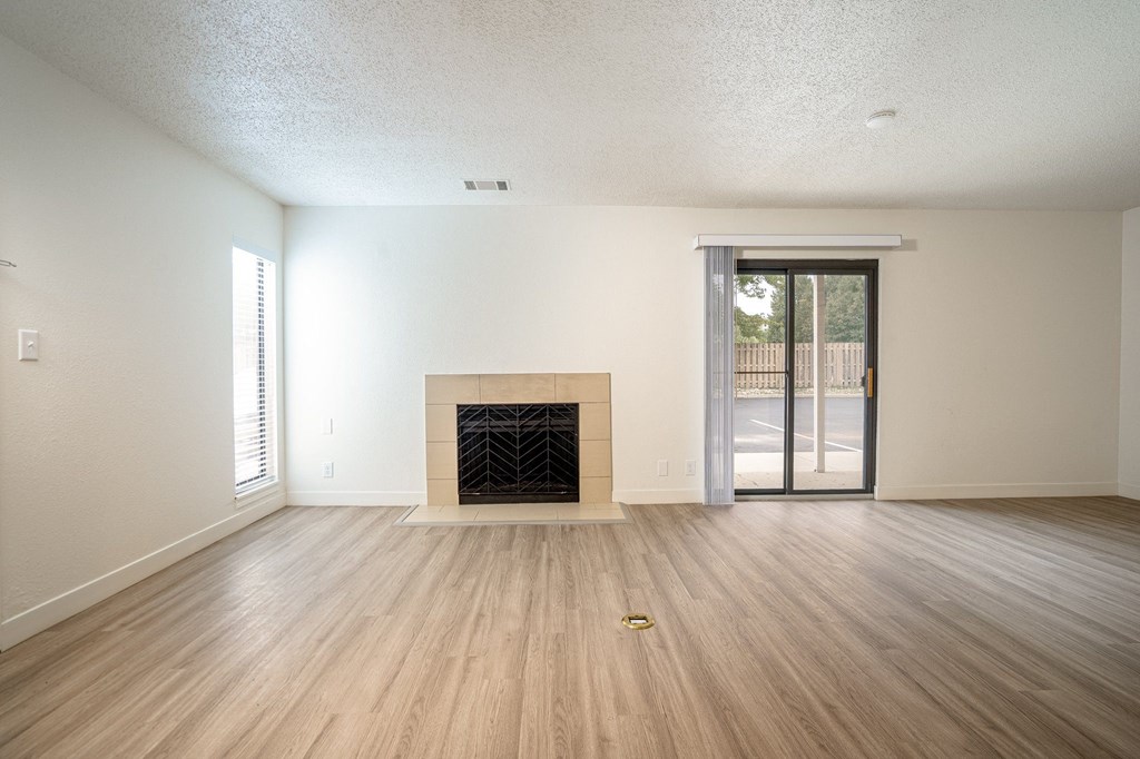 an empty living room with a fireplace and sliding glass doors