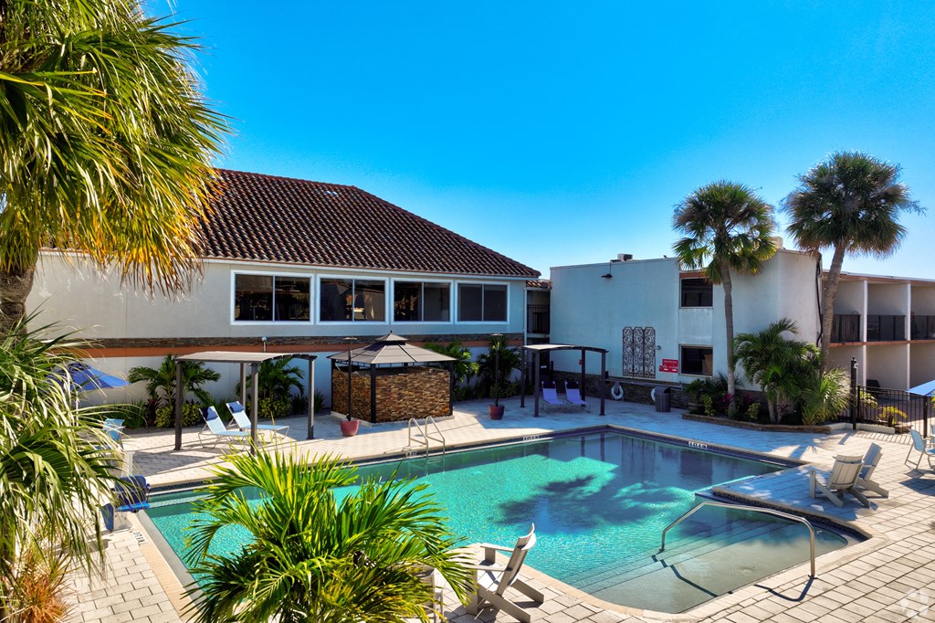 a swimming pool in front of a house with palm trees