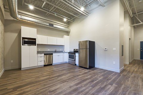 A kitchen with white cabinets and a black refrigerator.
