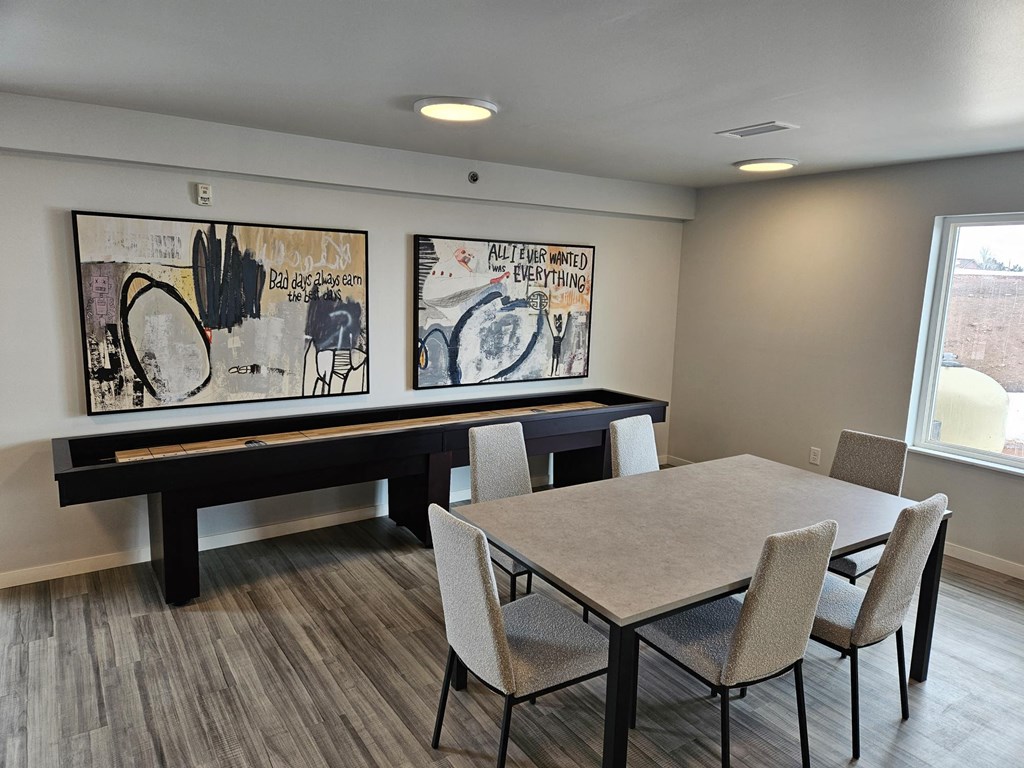 a room with a table and chairs and two paintings on the wall