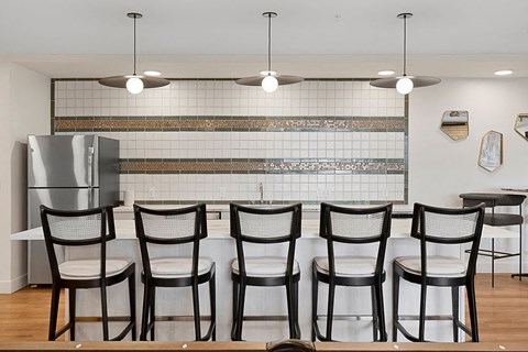 a kitchen with a long table with chairs and a refrigerator