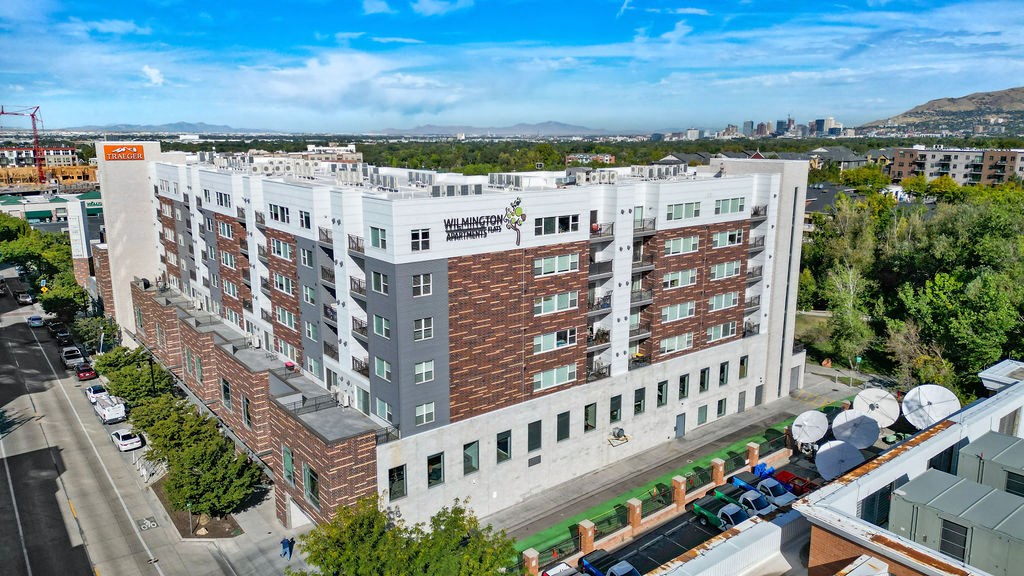 a large white building with many windows and a sign on the side of the building that says at Wilmington Flats Apartments, Salt Lake City, UT, 84106