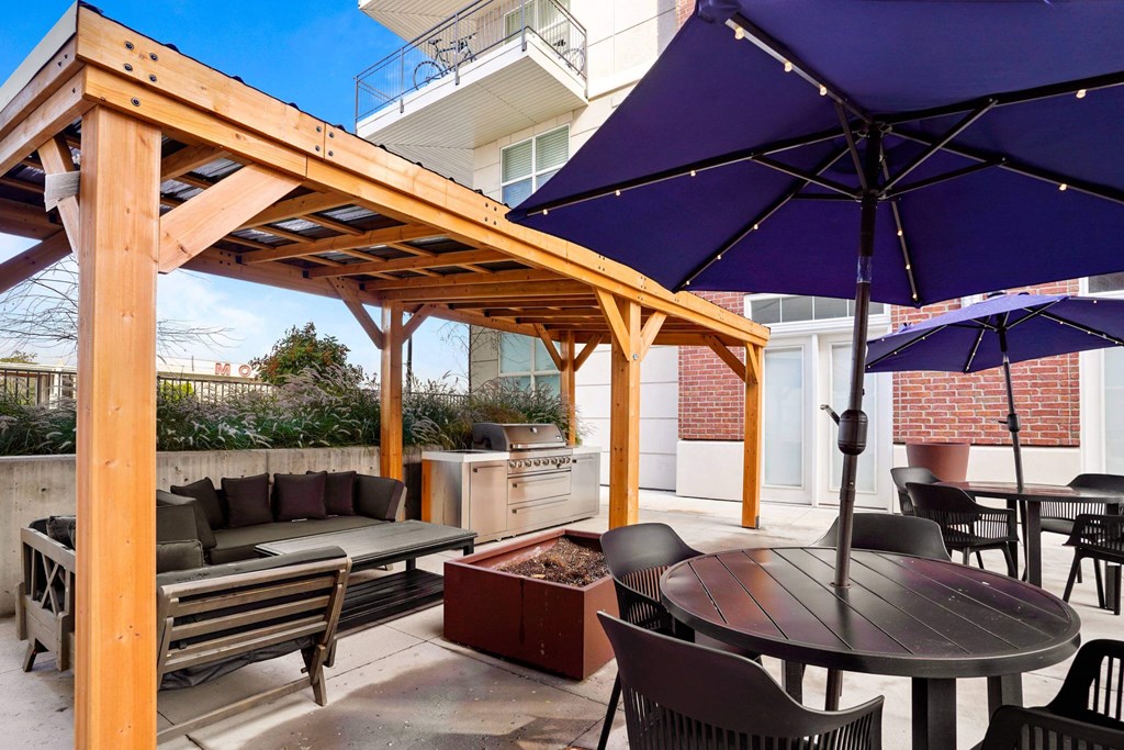 a patio with a wooden pergola and tables with umbrellas at 200 City View, Provo, UT