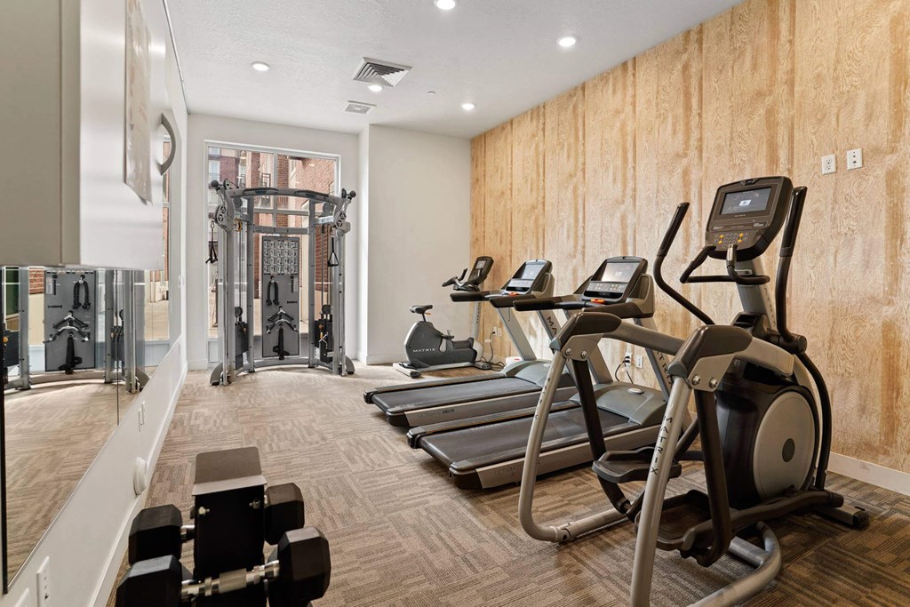 a gym with treadmills and other exercise equipment on a wooden wall at 200 City View, Provo