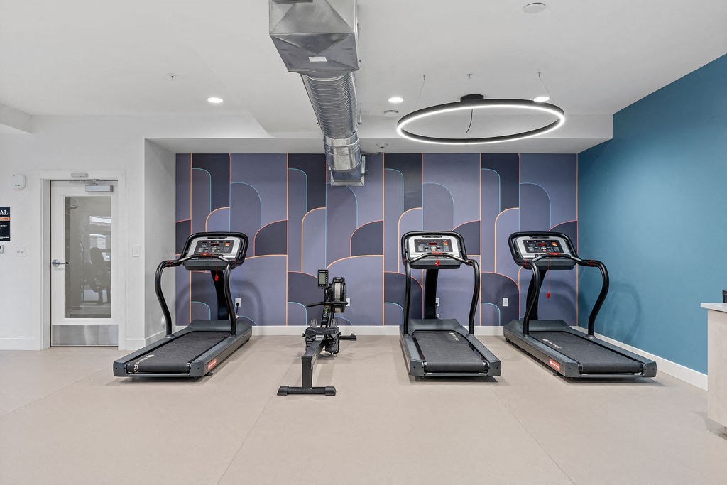 four treadmills in a gym with blue walls and a door at The Revival, Salt Lake City, 84101