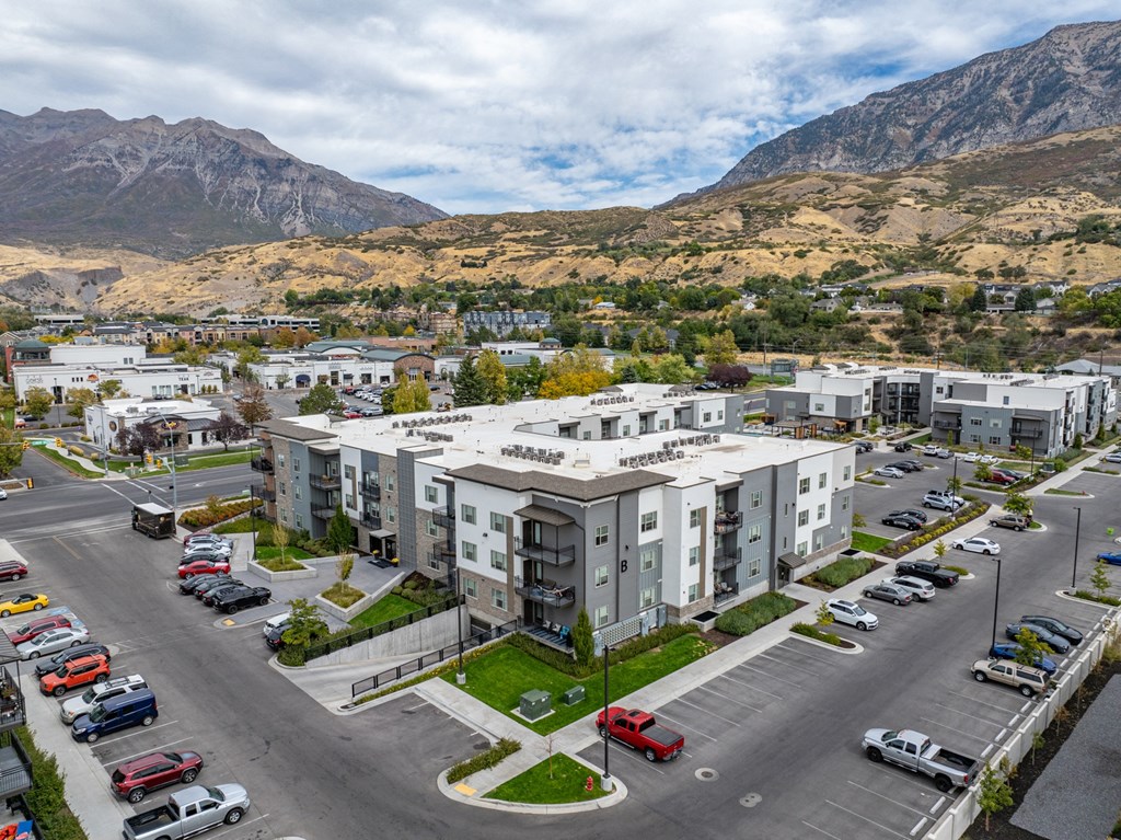 an aerial view of an apartment complex with mountains in the background at The Flats at Riverwoods, Provo