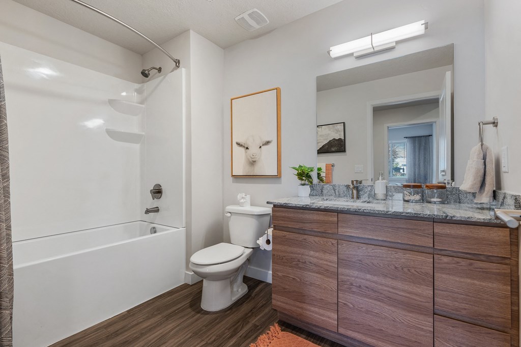 a bathroom with a toilet and a tub and a sink at The Flats at Riverwoods, Provo