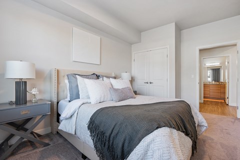 a bedroom with a large bed and a door to a bathroom at The Flats at Riverwoods, Provo, Utah