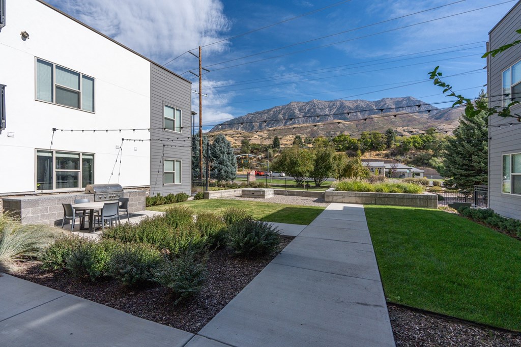 a sidewalk in front of a building with a table and chairs on it at The Flats at Riverwoods, Provo, Utah