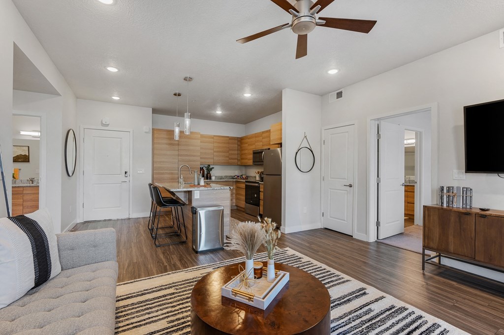 a living room with a couch and a table in front of a kitchen at The Flats at Riverwoods, Provo