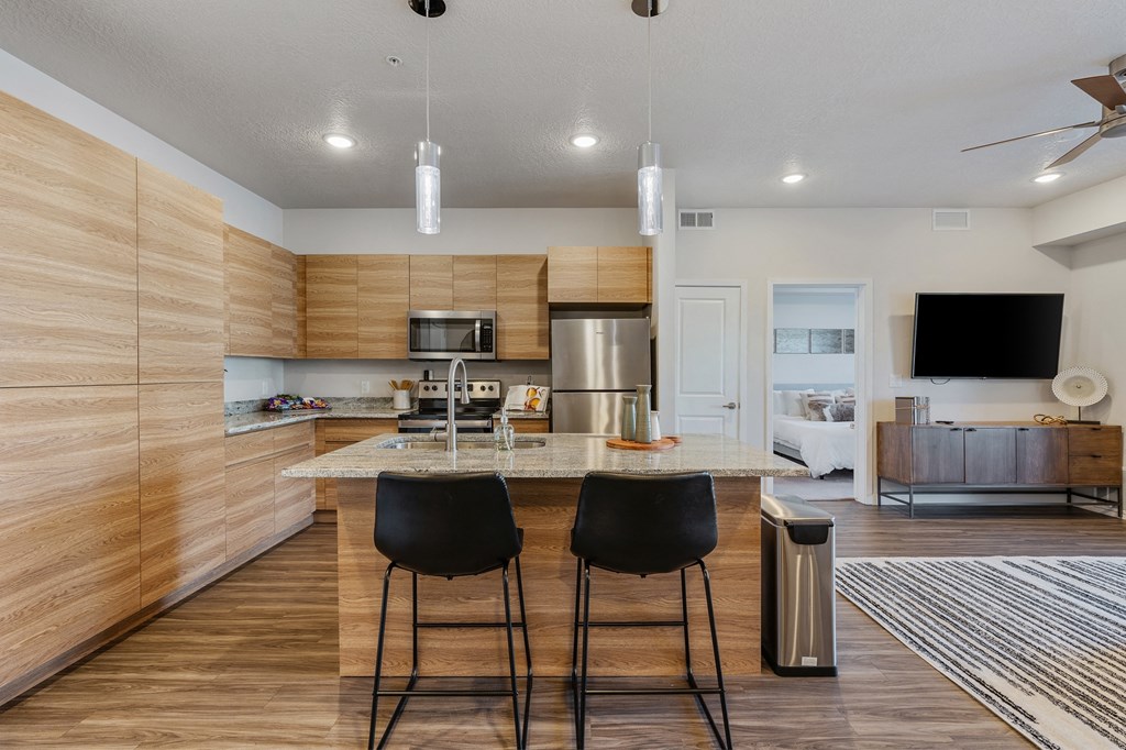 a kitchen with a center island with three stools at The Flats at Riverwoods, Provo, UT, 84604