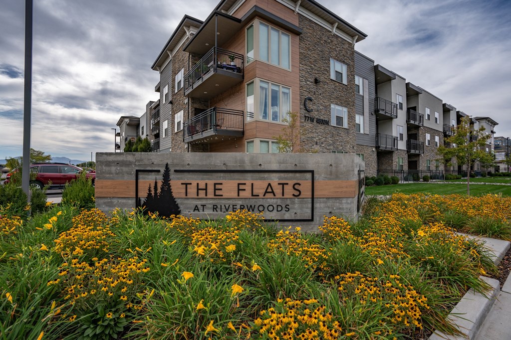 apartments sign in front of grass and flowers at The Flats at Riverwoods, Provo, Utah