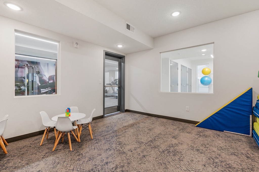 a play room with a table and chairs and a sliding glass door at The Flats at Riverwoods, Provo