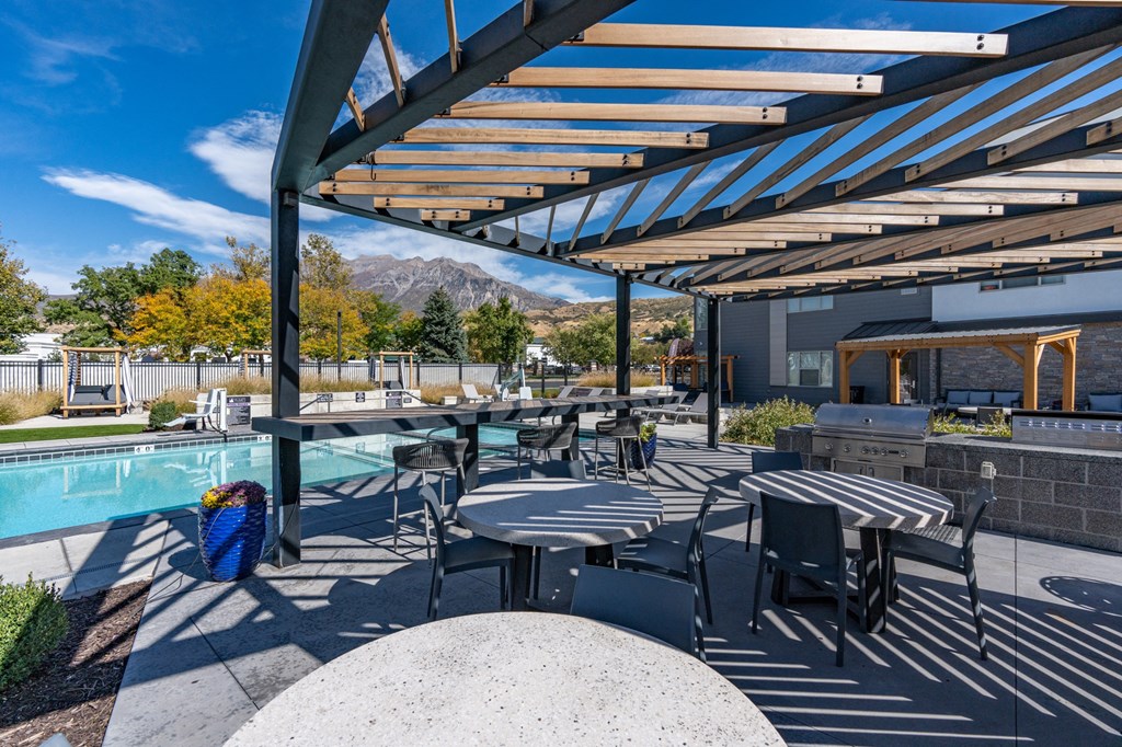 a patio with tables and chairs next to a pool at The Flats at Riverwoods, Provo, Utah