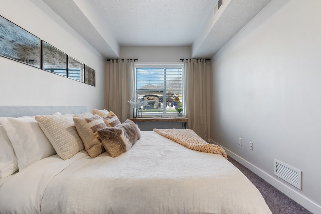 a bedroom with a large bed and a window at The Flats at Riverwoods, Provo, UT