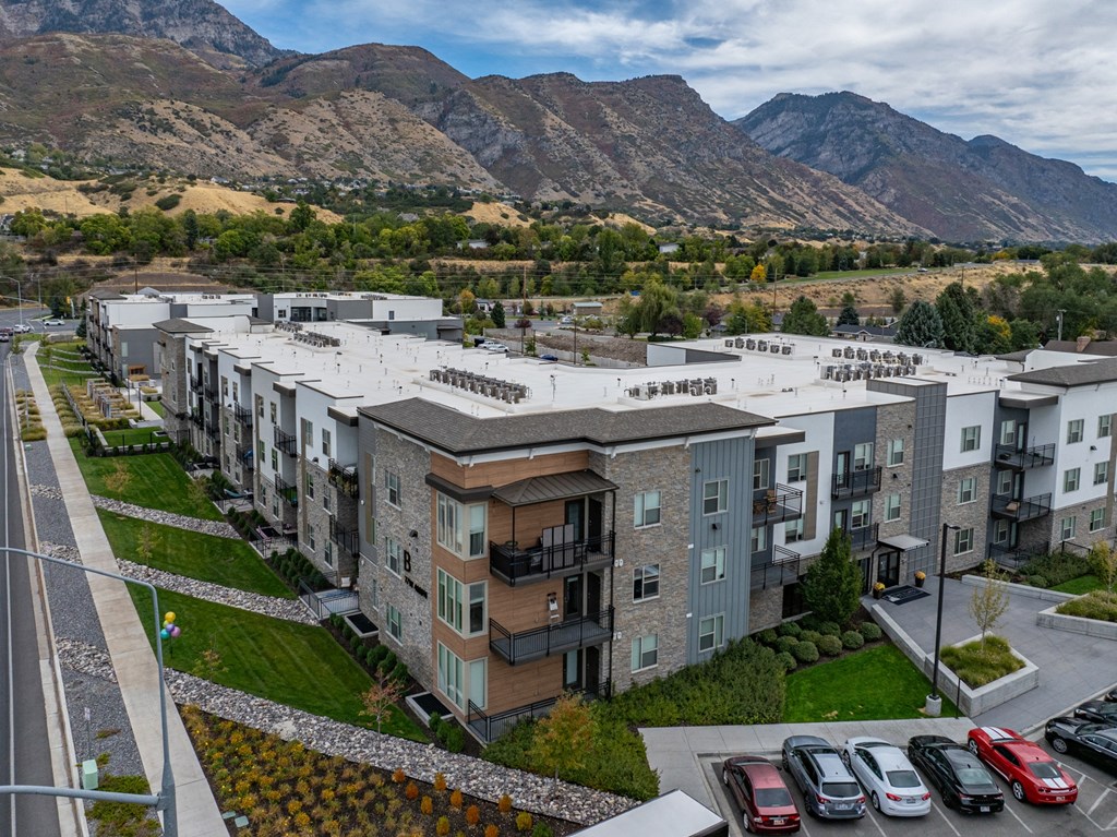 an aerial view of an apartment complex with mountains in the background at The Flats at Riverwoods, Provo, Utah