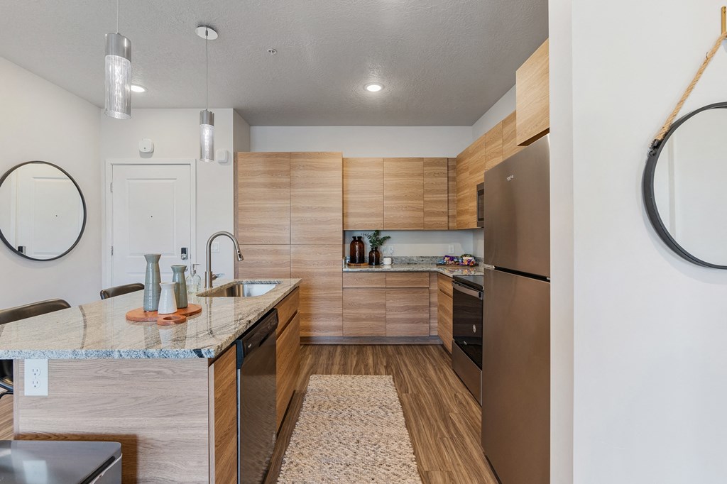 a kitchen with wooden cabinets and stainless steel appliances at The Flats at Riverwoods, Provo, Utah