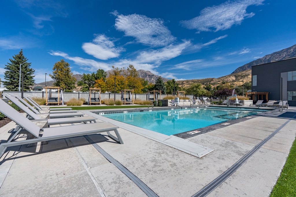 pool and lounge chairs with mountains in the background at The Flats at Riverwoods, Provo, Utah