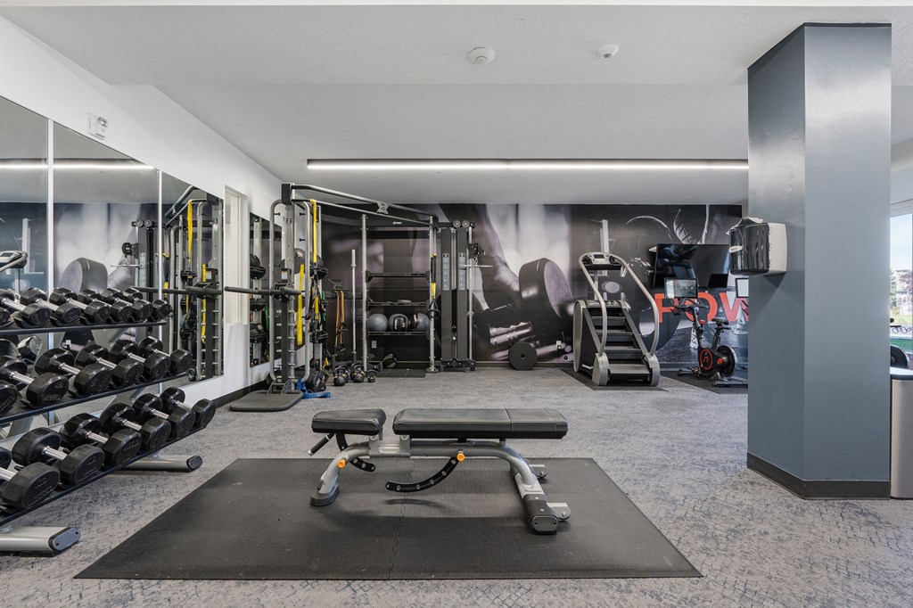 a gym with weights and cardio equipment on the floor and a wall with a mural at The Flats at Riverwoods, Provo, UT, 84604