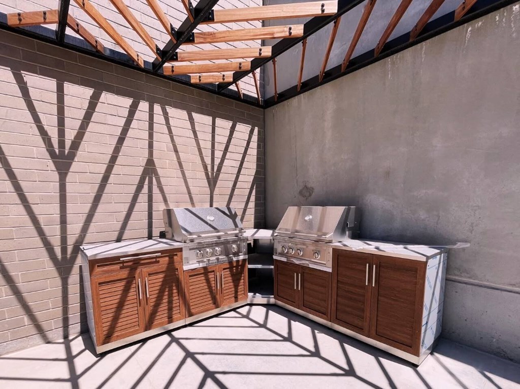 two grills in the corner of a patio with a roof