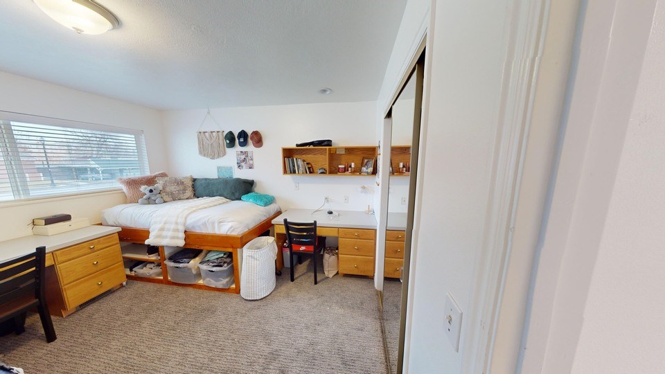 A bedroom with a bed, dresser, and chair.