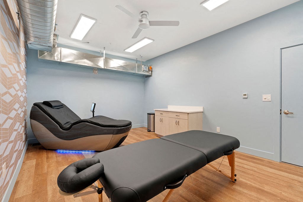 a treatment room with a black chair and a massage table at The Revival, Salt Lake City Utah