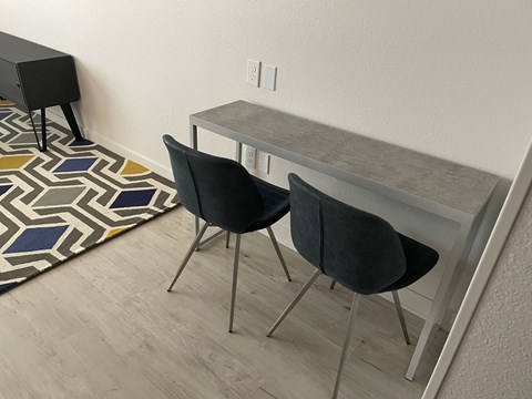 a small desk with two chairs in a room