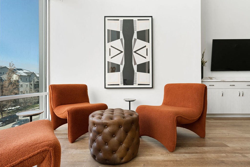 a living room with orange chairs and a print on the wall at The Revival, Utah
