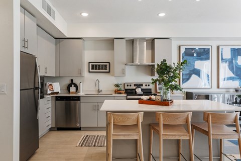 a kitchen with stainless steel appliances and an island with four chairs at Paperbox Lofts, Salt Lake City, UT