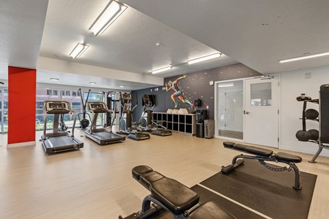 a gym with cardio machines and weights on a wooden floor at Paperbox Lofts, Salt Lake City, Utah