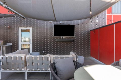 a patio with chairs and a television on a brick wall at Paperbox Lofts, Salt Lake City, UT, 84101