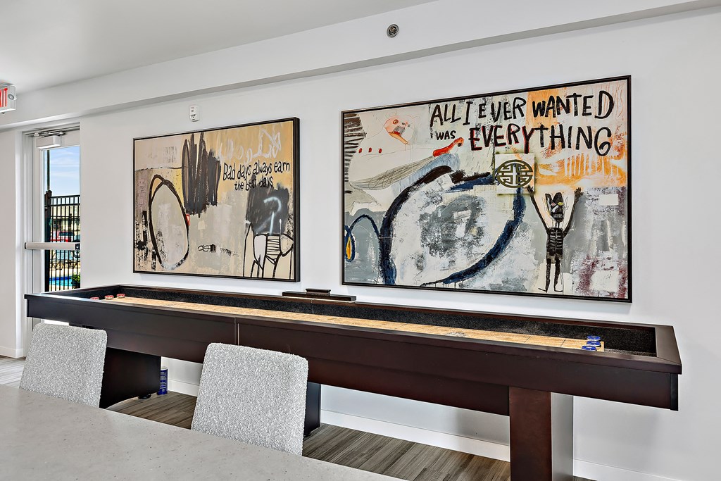 a room with a pool table and two paintings on the wall