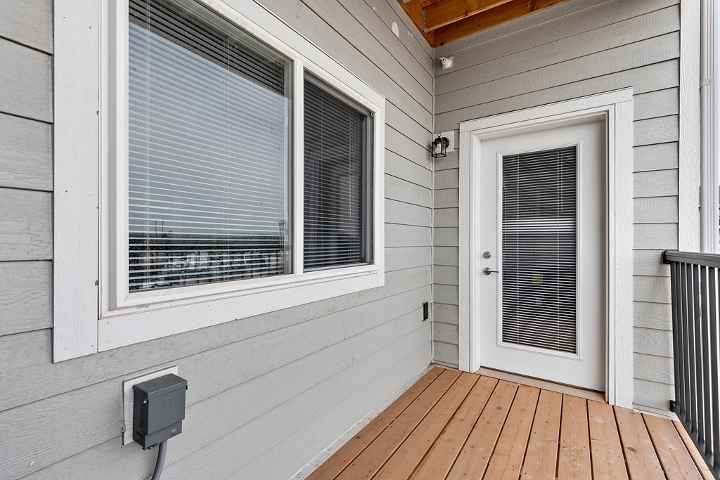 a front porch with a door and a window with venetian blinds