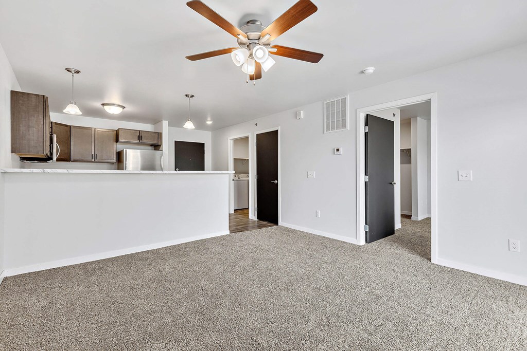 a living room with a ceiling fan and a kitchen in the background at Red Rock Apartments, South Dakota 57702