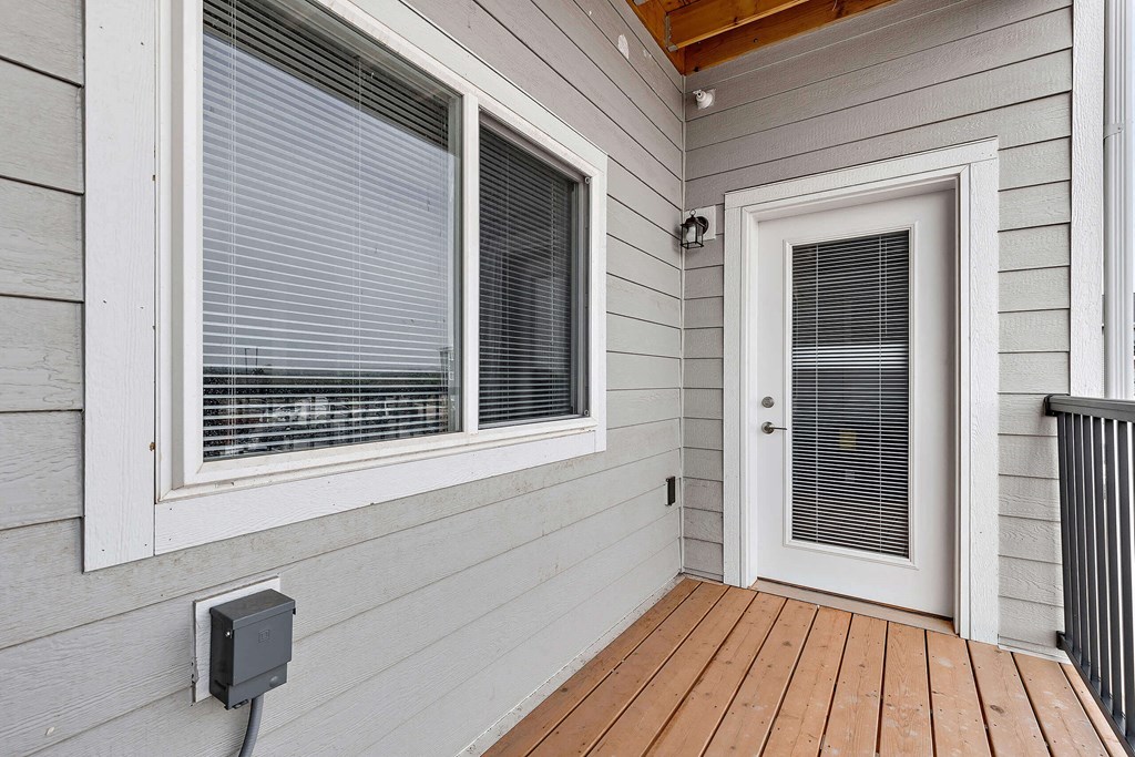 a front porch with a door and a window with venetian blinds at Red Rock Apartments, Rapid City, South Dakota