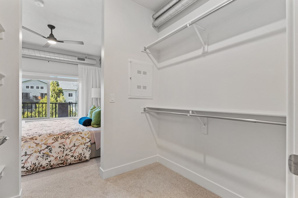 an empty bedroom with a bed and a closet with a sliding glass door at The Revival, Utah, 84101